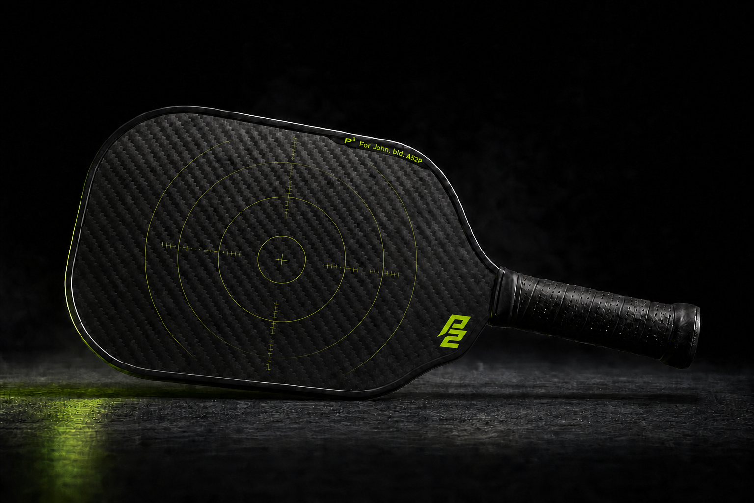 P2 raw carbon pickleball paddle in a dark engineering studio
